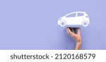 Small photo of Male hand holding car auto icon on grey background. Wide banner composition.Car automobile insurance and collision damage waiver concepts.