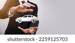 Small photo of Male hand holding car auto icon on grey background. Wide banner composition.Car automobile insurance and collision damage waiver concepts.