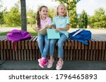 Small photo of Two cute pupils girls having fun after lessons in the schoolyard in sunny day. Children playing and laughing. Schooldays with friends. Concept back to school