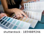 Small photo of Close-up of two women choosing samples of wall paint. Interior designer consulting a client looking at a color swatch. House renovation concept
