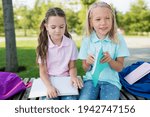 Small photo of Two cute pupils girls having fun after lessons in the schoolyard in sunny day. Children playing and laughing. Schooldays with friends.