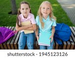 Small photo of Two cute pupils girls having fun after lessons in the schoolyard in sunny day. Children playing and laughing. Schooldays with friends.