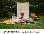 Small photo of Outdoor cinema theater Backyard Family outdoor movie night with kids. Sisters spending time together, watching cimema at backyard DIY Screen with film. Summer outdoor weekend activities with children