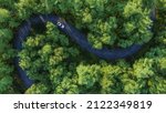 Small photo of Adventure morning road trip in the forest, aerial view of a car on deep jungle road. On The Road Again concept.