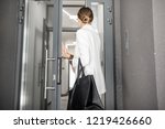 Young business woman in white suit entering to the hall of the modern residential building, back view