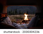Picnic with a big bonfire in a bowl, view from a vehicle interior. Traveling by car in the mountains, romantic atmosphere concept