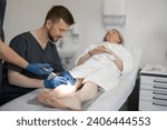 Small photo of Phlebologist makes injections into a vein, performing sclerotherapy on the veins of women's leg. Concept of medical treatment of varicose veins