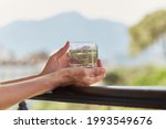 Girl holds in her hands a glass of homemade cocktail with herbs in front of mountains. Summer wallpaper close up.