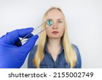 Small photo of Conceptual shot of an eye crystalline lens replacement. Ophthalmic surgery. Return of sight. Removal of cataracts. Surgical intervention in the eyeball. Doctor holds the implant near the patient