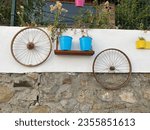 Small photo of Flowers in metal pots hung on the garden wall and decoration elements hung on the wall. Ornaments hung on the walls in the streets of Aegean village.