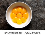 Bright yellow egg yolks in a white bowl with stone floor as background