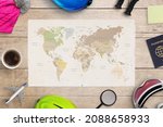 Planing ski trip concept. World map on wooden table surrounded by ski equipment, passport and plane toy. Top view, flat lay