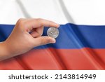 Small photo of Russian ruble coin in hand. Fag of Russia in the background