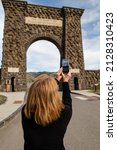 Gardiner, Montana, USA, May 27th, 2021 Tourist taking a pic of the Historic Roosevelt Arch in Montana at the North Entrance of Yellowstone National Park, vertical