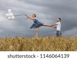 Small photo of Man Holding back woman flying with balloons