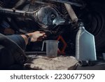 Small photo of Changing the oil in the front differential of an off-road vehicle, truck with four-wheel drive. Car service. Tools and spare parts. Male hands, mechanic. View from the first person