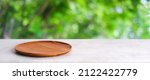 Small photo of Empty wooden plate on white table over blur green trees nature with bokeh background, Blank wood dish for food display montage banner template, muck up, poster, wallpaper