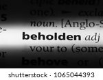 Small photo of beholden word in a dictionary. beholden concept.
