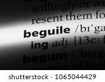 Small photo of beguile word in a dictionary. beguile concept.