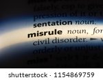 Small photo of misrule word in a dictionary. misrule concept.