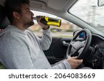 Small photo of Man drinks alcohol while driving the car. Irresponsible behavior