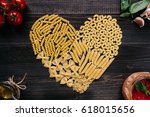 Dried pasta in heart shape top view. Pasta and vegetables on the dark wooden table.