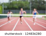Female athletes running towards finish line on track field