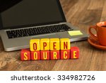 Open Source written on a wooden cube in front of a laptop