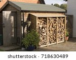 Log store standing against a garden shed. Logs stacked in a garden. UK