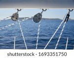 Small photo of Close-up view of sailboat ropes at sunny weather, pulleys and ropes on the mast, Yachting sport, ship equipment, sea is on background