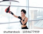 Small photo of sede view shot of pleasant female in black sportswear dealing a blow to little red and black speed bag at gym. fetch a blow