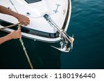 Small photo of Man s hand with boat rope. Yachtsman moors his motor boat at jetty. Close up hands and bow of the boat.