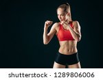 strong slim girl with ponytail is working out in boxing classes. close up photo.. isolated on the black background. poxing posture. position. competition