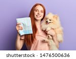 red-haired pretty positive girl controlling pissing process of her pet. close up portrait isolated blue background