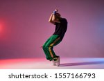 Modern hip hop dancer frozen in movie, standing on tiptoe, covering head with hands, expressing dance element, practicing in dance studio, full of energy break dancer