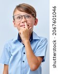 Small photo of Boy pokes nose with finger. Caucasian child pulls out the boogers. Bad manners. Misconduct. Little boy in eyeglasses spectacles looking up, wondering, isolated on white studio background
