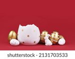 Small photo of Golden and white easter eggs with stripes and dots, eggcup and bunny figure on dark red background with copy space