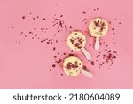 Ice cream lolly with white chocolate, coconot and dried raspberry fruit pieces on pink background