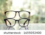 Small photo of Two black shortsighted or nearsighted eyeglasses on white acrylic table, Bokeh green garden background, Close up & Macro shot, Selective focus, About Optical concept