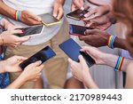 Small photo of Group of multiracial people with LGBT rainbow flag wristbands using their mobile phones. Diversity, LGBT, unity and technology concept.