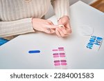 Small photo of Woman applying nail decals to her nails on a table. Manicure and beauty concept.