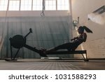 Woman doing cardio workout on rowing machine in the gym. Female exercising in fitness club.