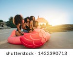 Group of girls sitting on a big inflatable pool toy on beach. Females sitting together on a inflatable swan at the sea shore on a sunny day.