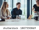 Small photo of Businessman smiling during a meeting. Business people smiling after a productive meeting in a conference toom.