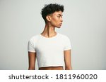 Gay man wearing crop top and earring looking away. Young androgynous man wearing earring against white background.