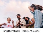 Small photo of Four multicultural friends dancing on the rooftop. Group of happy young friends laughing and having a good time during a party. Vibrant young people having fun together on the weekend.