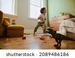 Small photo of Playful young boy mimicking a t-rex dinosaur during playtime at home. Creative little boy having fun while standing in his play area.