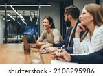 Small photo of Happy businesswoman laughing while leading a meeting with her colleagues. Group of diverse businesspeople working together in a modern workplace. Business colleagues collaborating on a project.