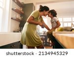 Small photo of Affectionate mother touching noses with her young son in the kitchen. Cheerful mother and son looking at each other fondly. Loving single mother bonding with her son at home.