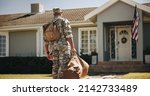 Small photo of Patriotic young soldier walking towards his house with his luggage. Rearview of an American serviceman coming back home after serving in the military.